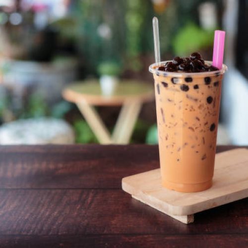 Ice bubble milk tea in takeaway glass on wooden plate – burry background Ice bubble milk tea in takeaway glass on wooden plate - blurry background
